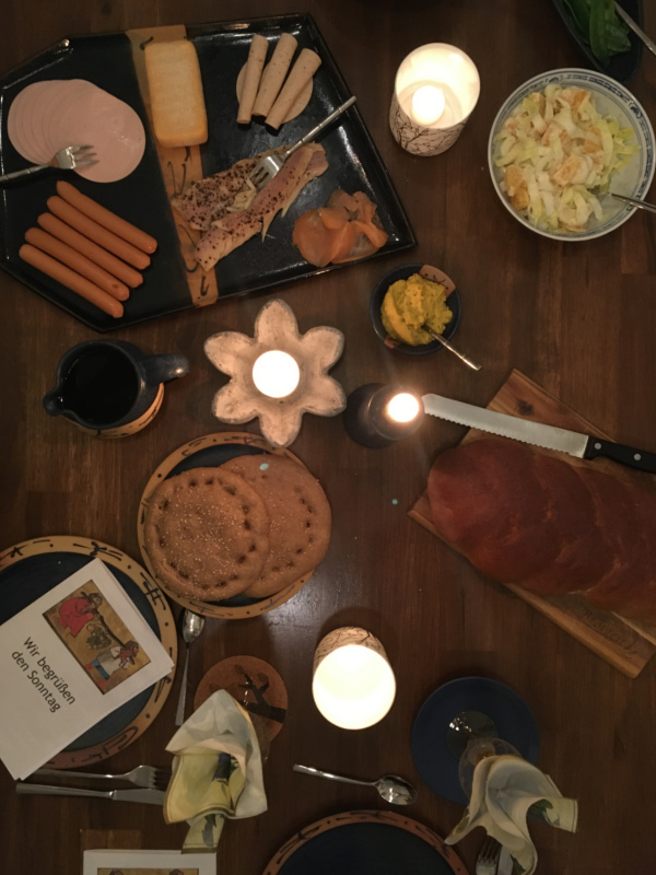 Jahresrückblick 2021 - Tisch mit Fladenbrot, Aufschnittteller, Kerzen und Heftchen, auf dem Sonntagsbegrüßung steht