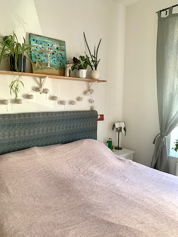 ein Bett, darüber ein Regal mit Pflanzen